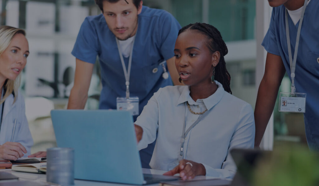 A team of healthcare professionals gather around a workstation in a facility representing Allina Health