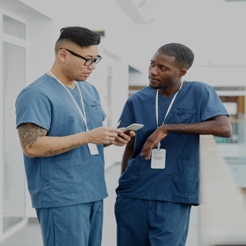 Two healthcare professionals in scrubs consult with each other in a facility representing Allina Health